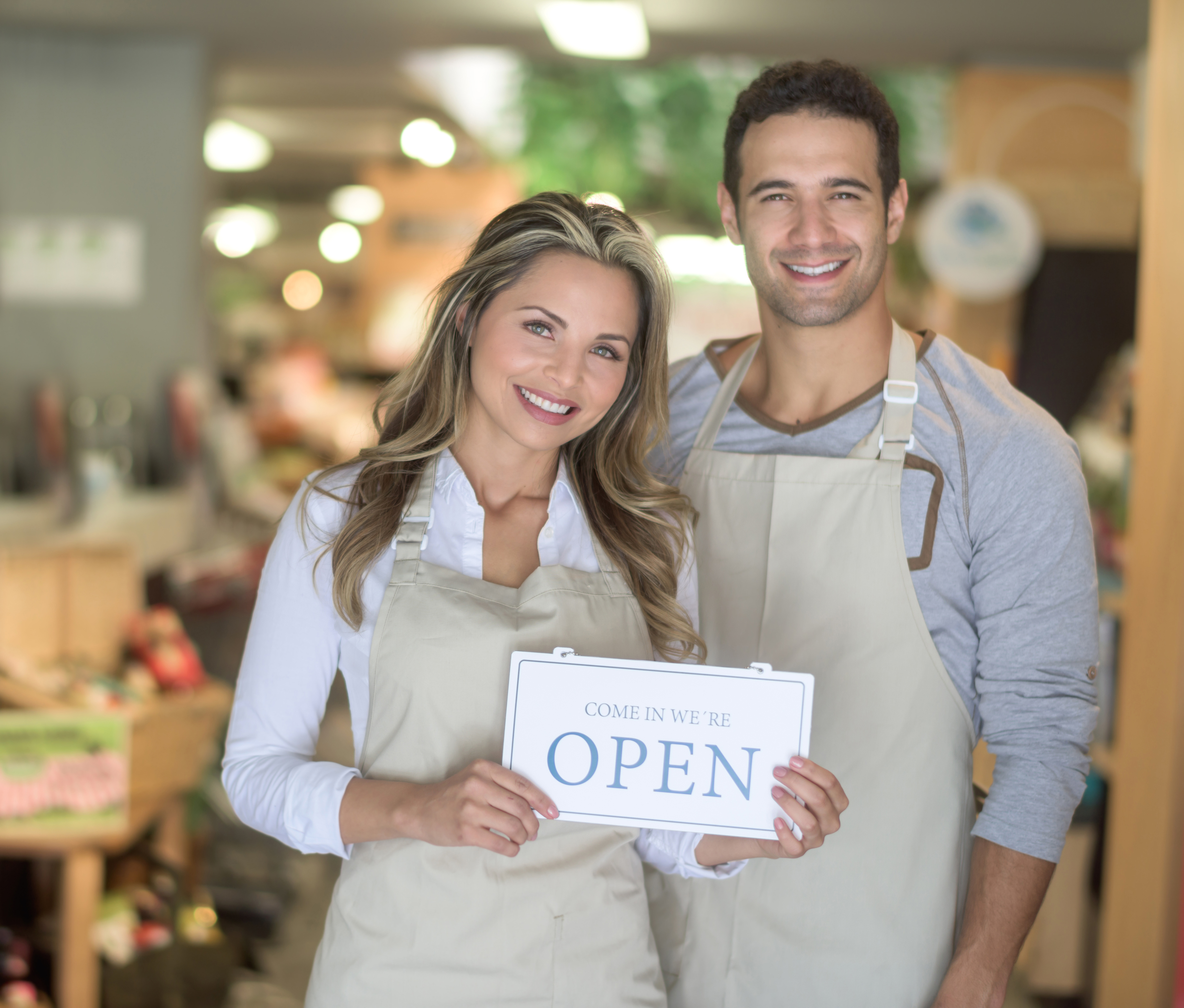 Couple owners holding Open sign at their franchise